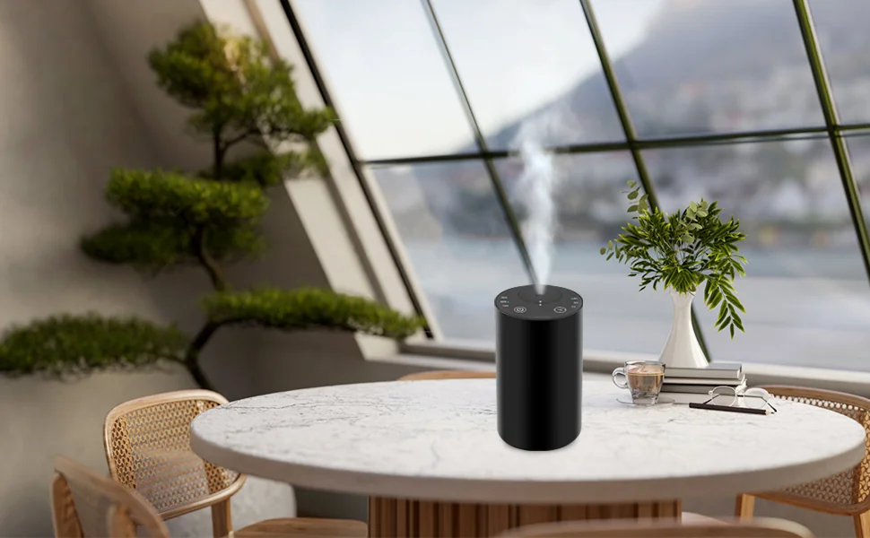 Black portable waterless essential oil diffuser on a lounge table by a window
